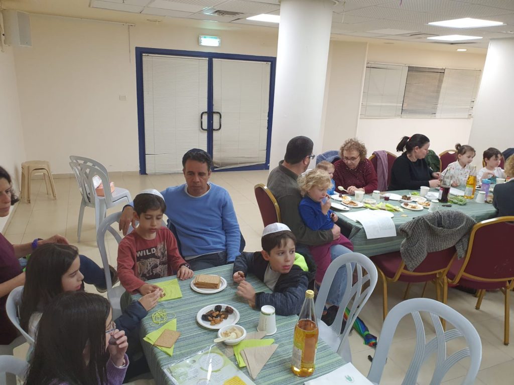 משפחות אוכלים בסעודה קהילתית
